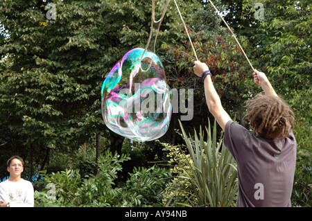 Straßenkünstler bläst Riesenseifenblasen am Jubilee Gardens in London, Großbritannien Stockfoto