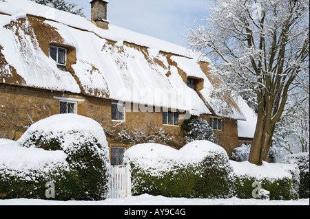 Englische Reetdachhaus mit Schnee bedeckt. Großen Tew, Oxfordshire, England Stockfoto