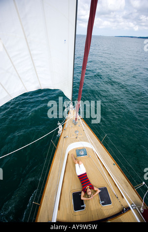 Frau Sonnenbaden an Deck von sailing Yacht, Cowes, Isle Of Wight, Großbritannien Stockfoto