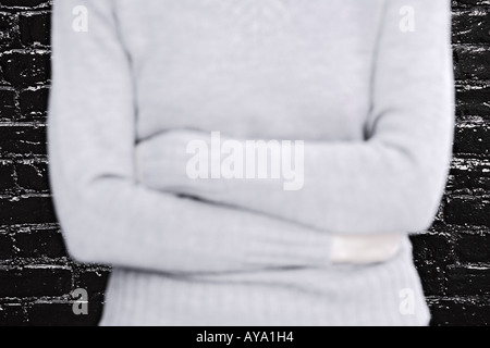 Nahaufnahme einer jungen Frau mit verschränkten Armen vor Brick Wall Brooklyn New York City Stockfoto