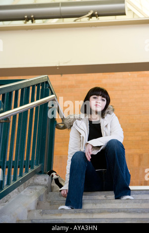 Porträt einer jungen Frau sitzt an der Spitze eine Betontreppe Stockfoto