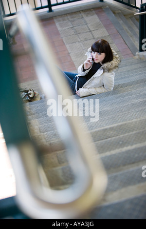 Porträt einer jungen Frau am unteren Rand einen Flug der Treppe und auf einem Handy Stockfoto