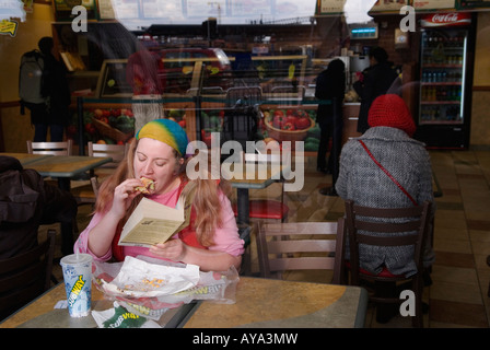 U-Bahn-Fast-Food-Outlet-Café, Frau liest ein Buch und isst und trinkt kohlensäurehaltiges Getränk. Stratford East London, England 2008 2000er Jahre, Großbritannien HOMER SYKES Stockfoto