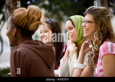 Ansicht von vier jungen Frauen im Gespräch beim Sitzen am Tisch im Garten Stockfoto