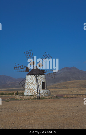 Schwarz / weiß Windmühle Bergkulisse in Wüste auf Fuerteventura im März. Stockfoto