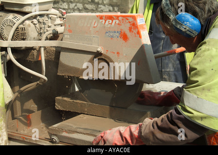 Nahaufnahme des Arbeiters durch Beton Pflastersteine für Straße arbeiten sah eine kreisförmige betriebenen high-Speed-Trennscheibe mit Stockfoto