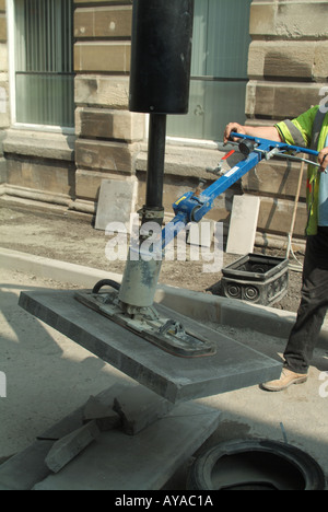 Nahaufnahme des Arbeiters mit einem angetriebenen Saug Gerät um zu heben Sie schwere Straßenpflaster Platte vom Stapel in gewünschte position Stockfoto