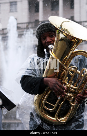 Musiker spielen durch Schnee auf dem Trafalgar Square bei Rallye um die Olympische Fackel in London begrüßen Stockfoto