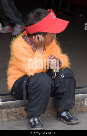 Tibetischen jungen sitzen an der Haustür eines Geschäfts in der Barkhor, shopping-district in Lhasa-Tibet Stockfoto