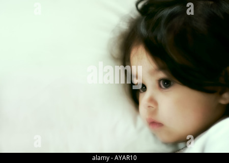 Kleines Mädchen im Bett liegend in tiefen Gedanken Stockfoto