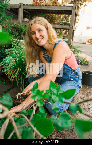 Porträt einer jungen Frau, die auf einen jungen Baum in einer Gärtnerei Stockfoto