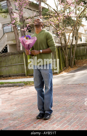 Lächelnde junge Mann auf Straße halten Blumenstrauß Stockfoto
