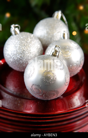 Splitter Weihnachtskugeln auf roten Platten vor Baum Stockfoto