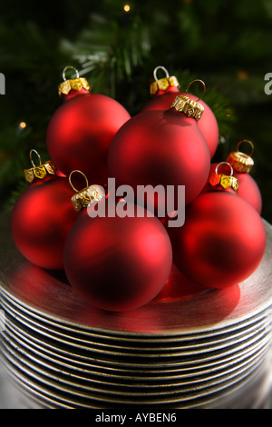 Rote Weihnachtskugeln auf Splitter Platten vor Baum Stockfoto