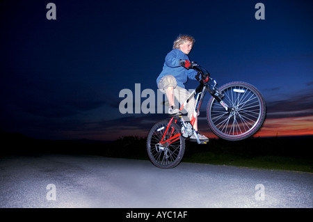 Ein kleiner Junge einen Wheelie auf seinem Mountainbike auf Heu zu bluffen, Powys, Wales, UK zu tun. Stockfoto