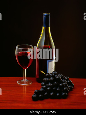 Flasche Rotwein mit einem Glas Wein und Trauben Stockfoto