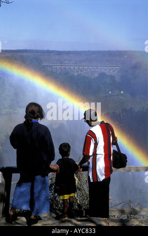 Eine Familie viel Freude beim Betrachten des doppelten Regenbogens in der Gischt der Victoriafälle aus Sambia Seite Afrika Stockfoto