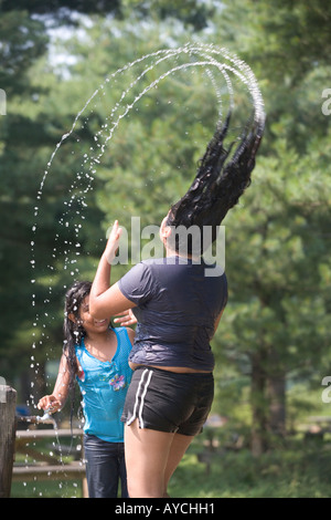 Eine Frau kühlt während einer Hitzewelle im Sommer durch Benetzung ihr Haar Stockfoto
