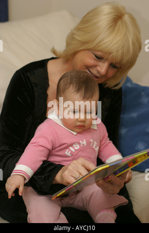 Eine Großmutter an ihre Enkelin Baby lesen Stockfoto