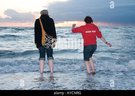Zwei Mädchen, Paddeln im Meer bei Abenddämmerung Studenten an der Aberystwyth University Cardigan Bay Wales UK Stockfoto