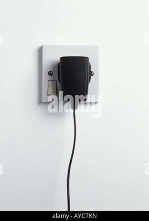 Handy-Ladegerät in weiße Steckdose auf weißen Wand eingesteckt Stockfoto