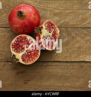 Ein Granatapfel und zwei Hälften auf Terrakotta Stockfoto