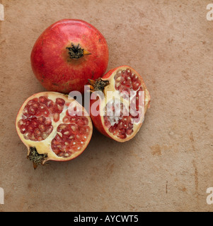 Ein Granatapfel und zwei Hälften auf Terrakotta Stockfoto