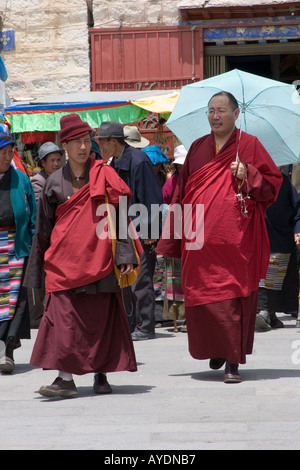 Zwei tibetische buddhistische Mönche, einer Abschirmung selbst mit einem Sonnenschirm vor der Sonne Fuß auf dem Barkhor Square in Lhasa-Tibet Stockfoto
