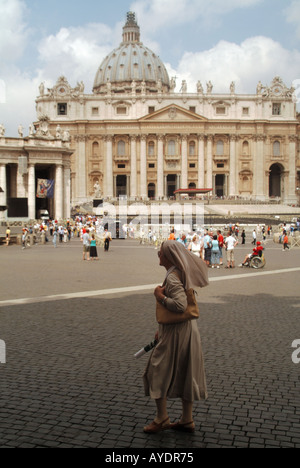 Nonne in religiöser Kleidung auf dem Petersplatz vor der Kulisse von Touristen und der Basilika dahinter an einem heißen, sonnigen Tag mit blauem Himmel in Rom Italien Stockfoto