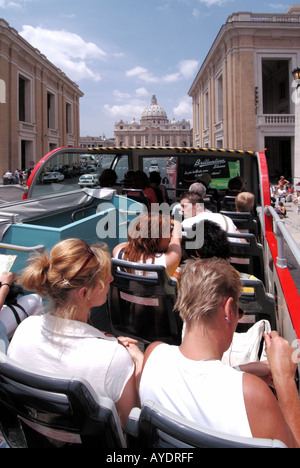 Zurück Ansicht Touristen Paar an Bord des roten Stop & Go Doppeldeckerbus mit offenem Oberdeck in der Nähe der Haltestelle am Petersplatz Basilika an einem heißen, sonnigen Tag in Rom Italien Stockfoto