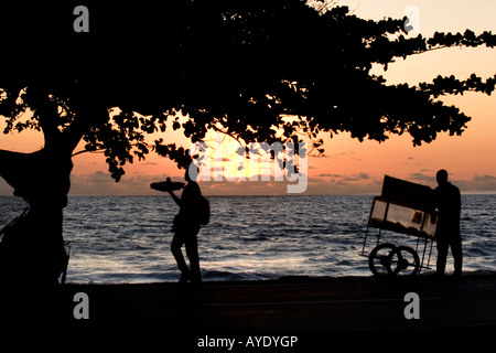 Afrikanische Straße Straßenhändler verkaufen Essen bei Sonnenuntergang am Strand Wasser am Ende des Tages, Libreville, Gabun Stockfoto