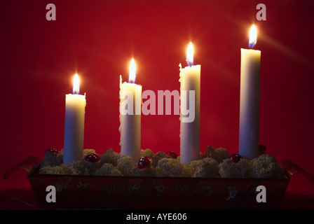 Vier weiße Advent Kerzen vor einem roten Hintergrund Stockfoto