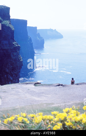 eine Frau sitzt auf dem Rand genießen die schönen Klippen von Moher-Irland Stockfoto