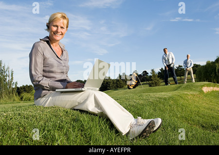 Eine Geschäftsfrau, die mit einem Laptop auf einem Golfplatz Stockfoto