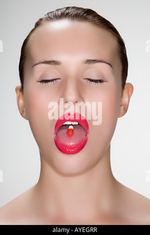 Frau mit Pille auf die Zunge Stockfoto
