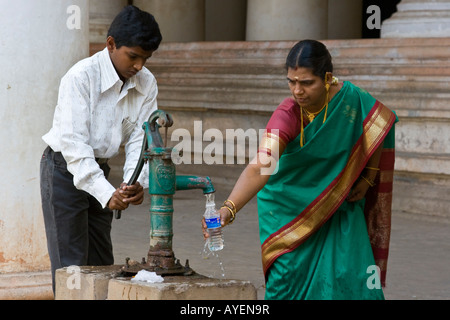 Indische Frau und junge füllt die Flasche Wasser von einer Pumpe im Tirumalai Nayak Palast in Madurai in Südindien Stockfoto