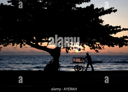 Afrikanische Straße Hawker Verkauf von Lebensmitteln mit seinem Karren bei Sonnenuntergang am Ende des Tages am Strand Wasser, Libreville, Gabun Stockfoto