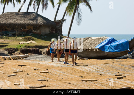 Westliche Touristen zu Fuß durch Trocknung Netze am Strand von Varkala Südindien Stockfoto