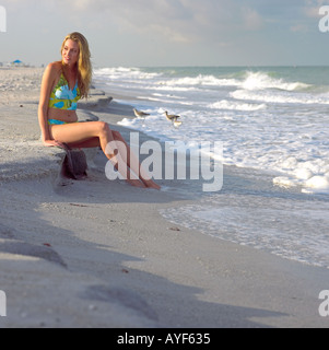 Junge Frau im Badeanzug sitzt friedlich an Indian Rocks Beach Florida USA-Küste in den frühen Morgenstunden Stockfoto