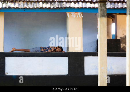 Indischer Junge, der in einem Tempelkomplex in Kerala, Südindien, liegt Stockfoto