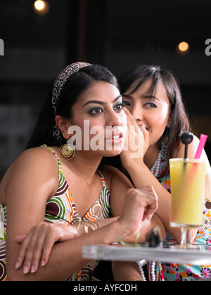 Junge Frau in Freunde Ohr flüstern Stockfoto