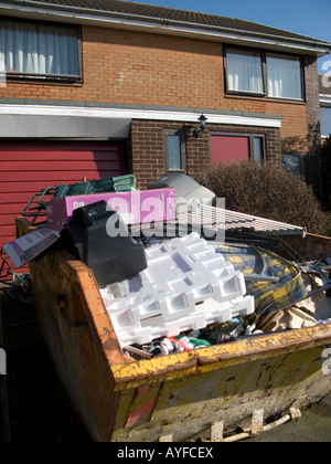 Ein überspringen voll von Junk-e-Haushalt und Müll vor Haus auf einem Vorort Wohnsiedlung, Aberystwyth Wales UK Stockfoto