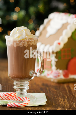Heiße Schokolade mit Schlagsahne neben Lebkuchenhaus Stockfoto