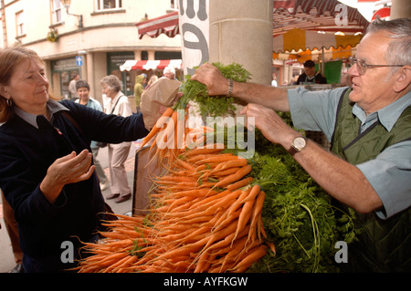 EIN KÄUFER, KAUF EINER REIHE VON KAROTTEN AUF DEM BAUERNMARKT IN STROUD GLOUCESTERSHIRE UK Stockfoto