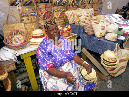 Eine große schwarze Frau afrikanischer Abstammung verkauft Stroh waren an einen offenen Markt in Nassau Stockfoto