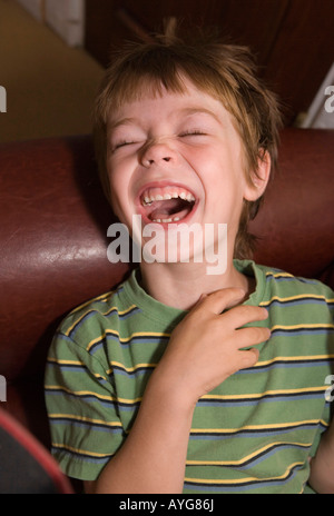 fünf Jahre alter Junge mit offenem Mund hart lachen Stockfoto