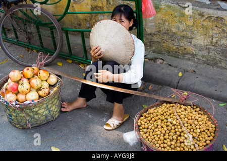 Frau trägt eine traditionelle vietnamesische Reis Hut verkauft frische Longan und Granatäpfel Hanoi Vietnam Stockfoto