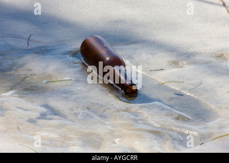 Leere Bierflasche verließ am Strand Stockfoto