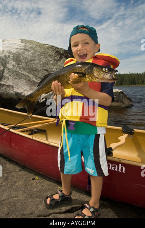 KLEINER JUNGE MIT GROßEN ZANDER ENTLANG NORTHERN ONTARIO SEE Stockfoto