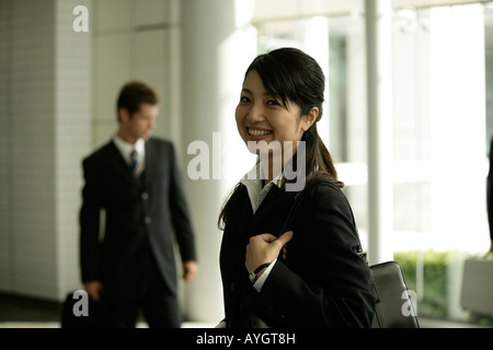 Porträt der Geschäftsfrau im Büro mit dem Geschäftsmann auf Hintergrund stehend Stockfoto